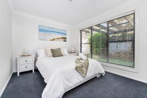 um quarto com uma cama e uma grande janela em Pacific Blue, Gerringong em Gerringong