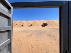 an open door in the desert with sand dunes in the background at Big dune camp in Ḩawīyah
