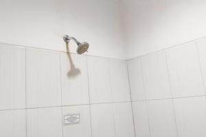 um chuveiro na casa de banho com paredes em azulejos brancos em RedDoorz near Living Plaza Palembang em Palimbão