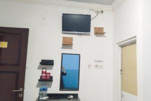 uma parede com uma televisão e um espelho numa parede em RedDoorz near Living Plaza Palembang em Palimbão