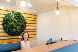a woman sitting at a desk in an office with a plant on the wall at Holbrook Motel in Holbrook