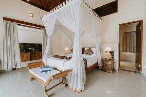 - une chambre avec un lit à baldaquin dans l'établissement Meng Bengil Villa, à Ubud