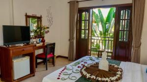 una habitación con TV y una mesa con un pastel. en Villa Indochine d'Angkor, en Siem Reap