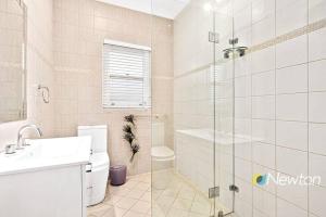 a bathroom with a toilet and a sink and a shower at Sunny Apt on The Esplanade - Aircon in Cronulla