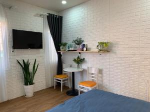 1 dormitorio con una pared de ladrillo blanco con mesa y sillas en Bồ Công Anh hostel, en Xuan An