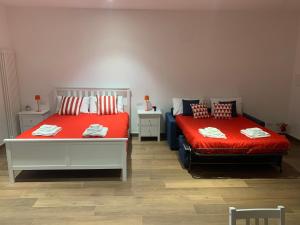 2 camas con sábanas rojas en una habitación en Due Golfi Apartment, en SantʼAgata sui Due Golfi