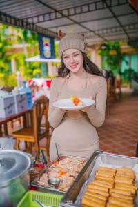 Eine Frau hält einen Teller Essen in der Hand in der Unterkunft Siam Tara Resort Chiangkhong in Chiang Khong