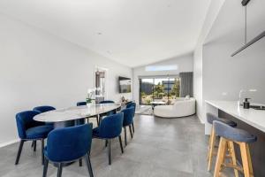 a kitchen and dining room with a table and blue chairs at Opulence Cove in Cape Paterson