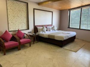 - une chambre avec un grand lit et une chaise dans l'établissement HOTEL RADHE Anand, à Anand