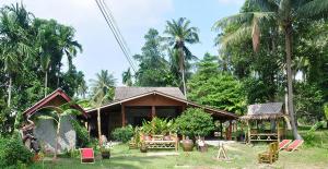 a small house in a yard with palm trees at Jungle Garden Bungalows in Hinkong