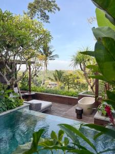 una piscina en un jardín con árboles en The Ridge Bali, en Ubud