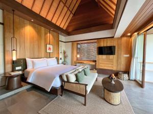 a bedroom with a large bed and a couch at The Ridge Bali in Ubud