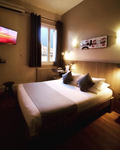 a bedroom with a large white bed with a window at Le Strasbourg Hotel in Montpellier