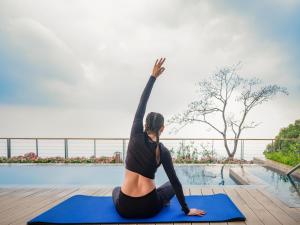 une femme faisant une pose de yoga près d'une piscine dans l'établissement The Westin Resort & Spa Himalayas, à Rishikesh