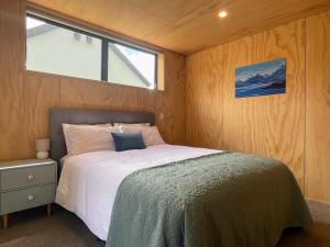 a bed in a small room with a window at Mill Creek Cottage in Arrowtown
