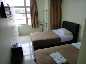 a hotel room with two beds and a television at Mines Inn Hotel in Gua Musang