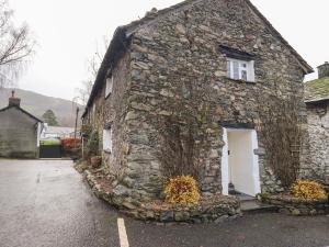 an old stone house with a white door at How Head Cottage in Ambleside