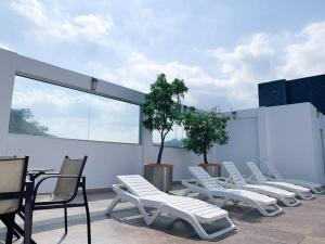 a row of white lounge chairs on a roof at Hermosa Suite con vista al rio! Piscina y Parqueo in Guayaquil