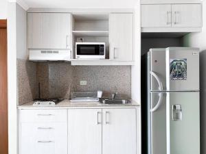 a kitchen with white cabinets and a white refrigerator at Hermosa Suite con vista al rio! Piscina y Parqueo in Guayaquil