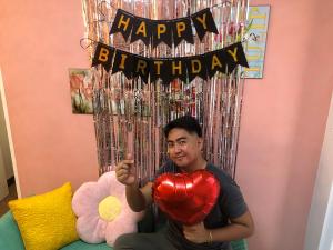 a man holding a heart and a happy birthday balloon at Staycations by SMS in Manila