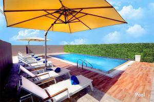 einen Pool mit Stühlen und einem großen gelben Sonnenschirm in der Unterkunft Grand Kingsgate Jaddaf Waterfront Hotel by Millennium in Dubai