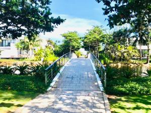 eine Brücke über einen Gehweg in einem Park in der Unterkunft Biệt thự 5PN Resort Sanctuary HỒ Tràm ll Bãi biển riêng ll hồ bơi BBQ in Xuyên Mộc