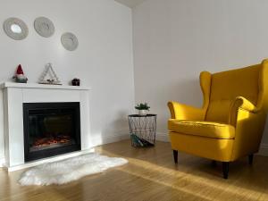 a living room with a yellow chair and a fireplace at Bucovina View apartment in Câmpulung Moldovenesc