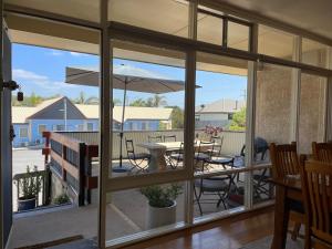 un porche cubierto con una mesa y una sombrilla en Portside Motel, en Port Campbell