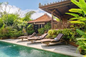 a group of lounge chairs next to a swimming pool at Villa Asrava Ubud in Ubud
