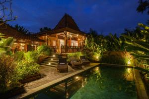 a villa with a swimming pool at night at Villa Asrava Ubud in Ubud