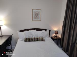 una camera da letto con un letto con lenzuola e cuscini bianchi di Sweet House B&B a Victoria