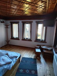 a bedroom with a bed and a table and windows at Сияние in Smolyan