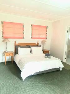 a bedroom with a large white bed with two windows at The Oaks Hotel in Richmond