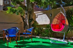 Egyptus Villa Hostel في الإسكندرية: كرسيين وأرجوحة في حديقة