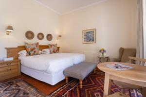 a bedroom with a bed and a desk and a table at Rozendal Stay in Stellenbosch