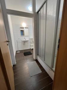 - un couloir avec une salle de bains pourvue d'un lavabo et d'une fenêtre dans l'établissement MWM Gästehaus, à Meine