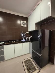 a kitchen with a refrigerator and a fan in it at Embun Selasih Homestay in Pasir Gudang