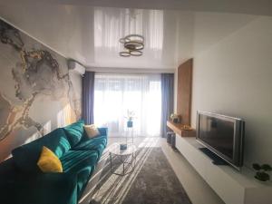 Una sala de estar con un sofá azul y un televisor. en Serene Ambiance Amazing 1BR with private parking, en Voluntari