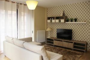 Una sala de estar con un sofá blanco y un televisor. en Apartamentos Vino y Camino, en Nájera