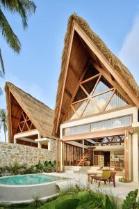 une maison avec un toit de chaume et une piscine dans l'établissement Tias Villas, à Kuta Lombok