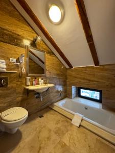 a bathroom with a tub and a toilet and a sink at Conacul Dima Predeal in Predeal