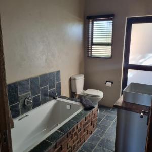 ein Badezimmer mit einer Badewanne, einem WC und einem Waschbecken in der Unterkunft Makhato Bush Lodge 114 in Bela-Bela