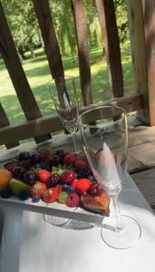 dos copas de vino y un plato de fruta en una mesa en Cabane perchée luxe avec jacuzzi Domaine du Marais Maisse, en Maisse
