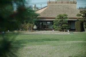a house with a grass yard with a building at Ryokan Onomichi Nishiyama in Onomichi