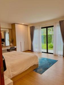 a bedroom with a large bed and a large window at 12_LUXURY VILLA COASTAR HỒ TRÀM RESORT ll Private pool ll large garden ll BBQ next to the HAMPTONS 300m - beautifull beach in Xuyên Mộc