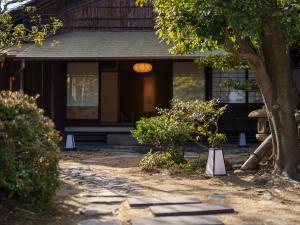 una casa con un árbol y una pasarela delante de ella en Ryokan Onomichi Nishiyama en Onomichi