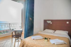 a bedroom with a bed with two pillows and a balcony at Poseidon Beach Hotel in Kastrosikia