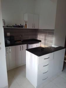 a kitchen with white cabinets and a black counter top at Mountain view apartment in Makadi Heights in Hurghada