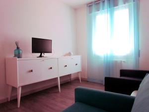 a living room with a tv on a white dresser at B&B Caorle For You in Caorle