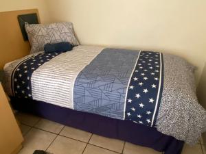 a bed with a blue and white quilt on it at Sunset Sands in Jeffreys Bay